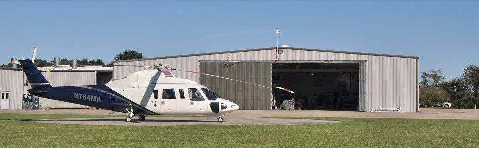 White and blue helicopter outside hanger at Arrow Aviation facility
